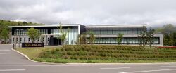 Rectangular windowed building, with landscaping and a sign in front labeled 'Lexus'.