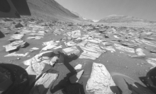 A Martian landscape taken by the Curiosity Rover, whose shadow is in the foreground.