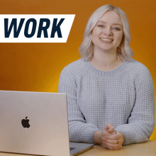 smiling woman in front of a laptop with an orange backdrop behind her