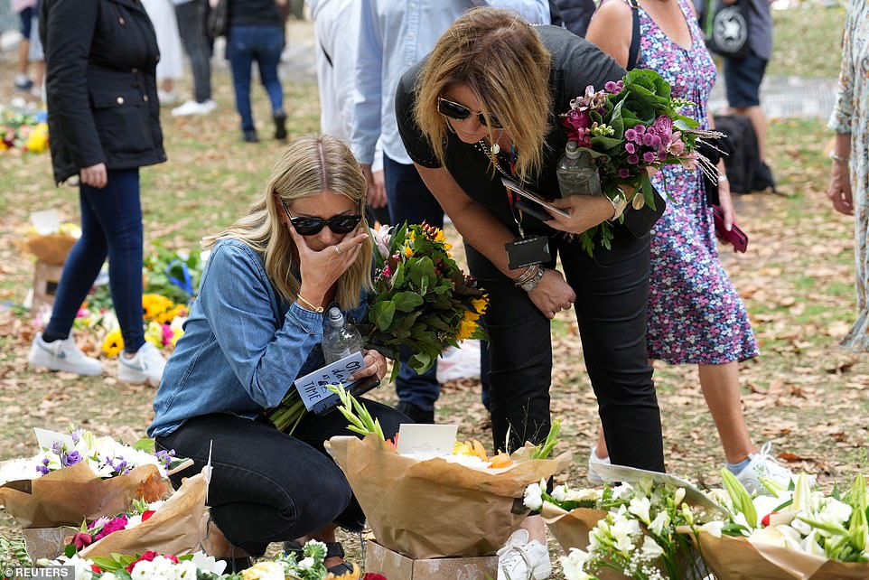 Two women read a message as they lay floral tributes to the late monarch at Green Park in central London on September 12