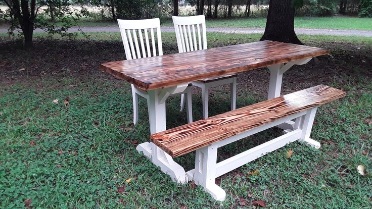 two white chairs and a wooden table in the grass