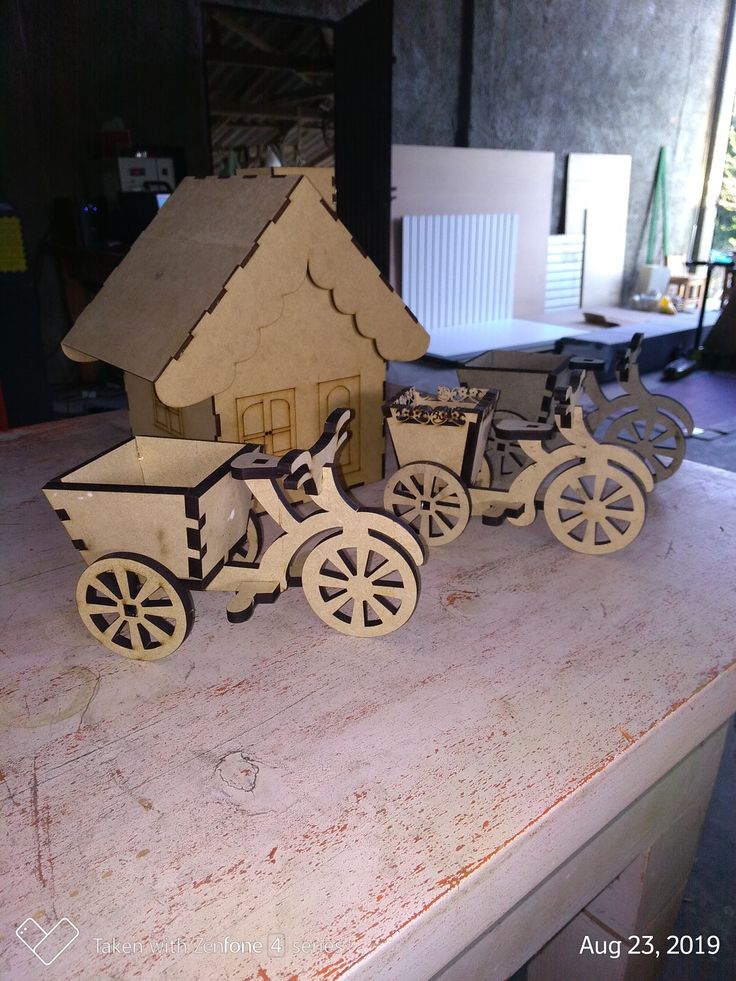 three wooden toy horses pulling a cart with a house on top and a horse ...