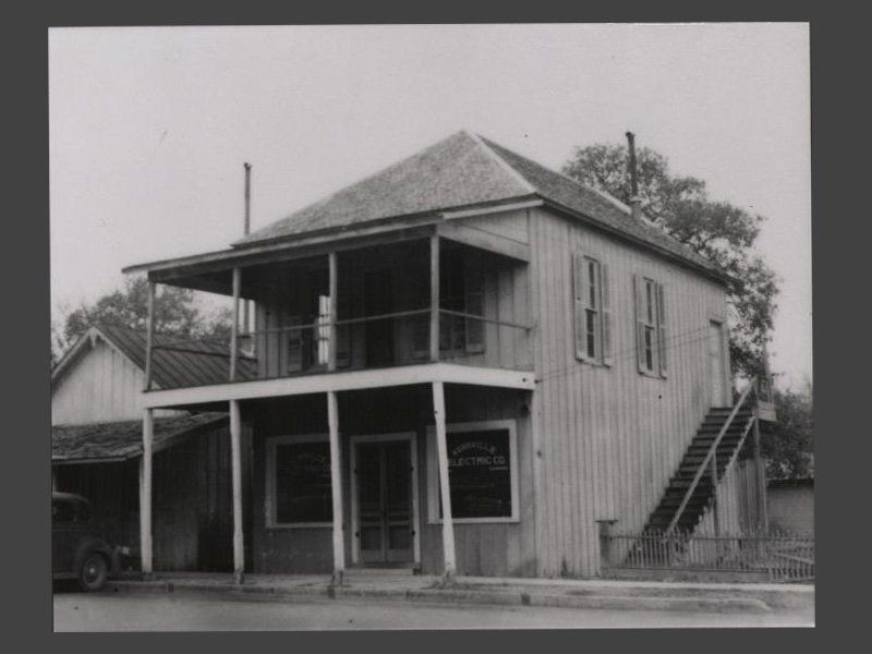 black and white photograph of an old building with two stories on the ...