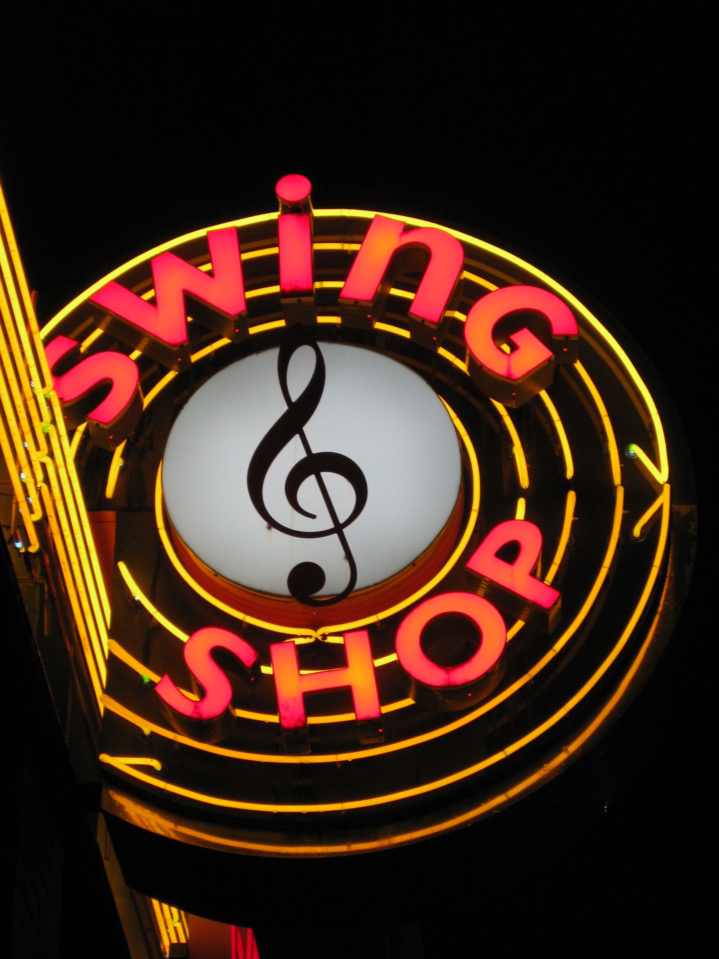 a neon sign that says swing shop with a treble