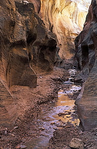 Close Up Photo of Black Rock Formation With Litter Amount of River in the Middle of Valley