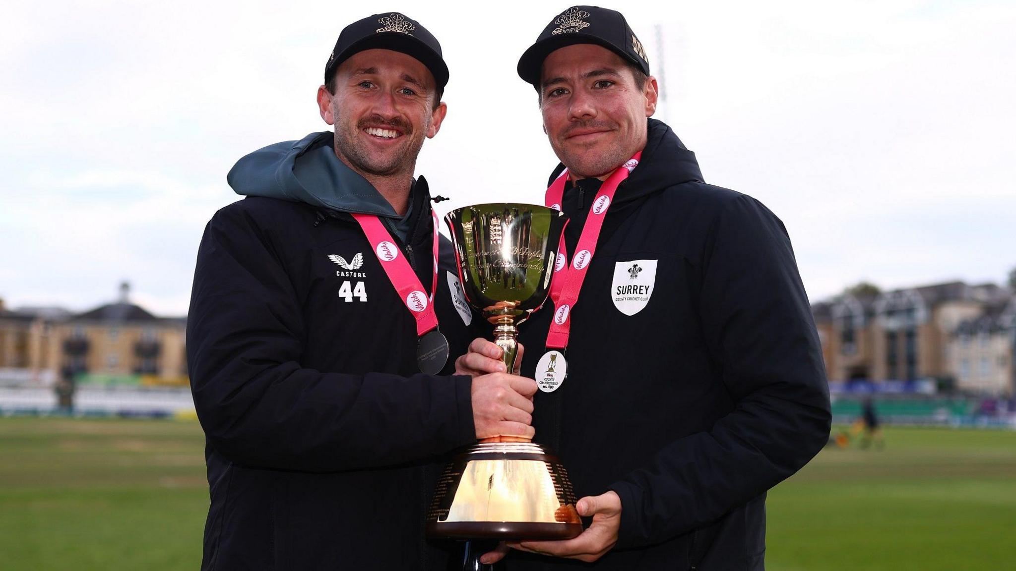 Surrey all-rounder Cameron Steel and captain Rory Burns holding the County Championship trophy