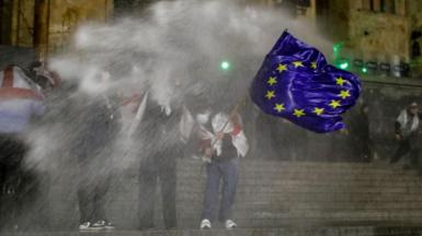 Protesters stand on the steps of parliament in Georgia as they are doused with water cannon