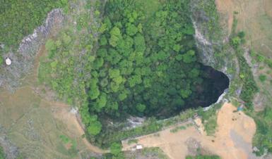 Aerial photo of a sinkhole dropping away in the middle of the forest in China's Guangxi province