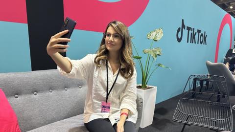 A woman holds a phone while sitting on a sofa