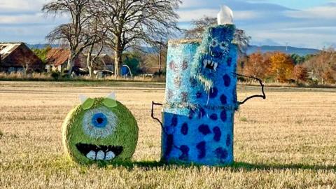 bales of hay decorated to make them look like monsters in a freshly cut field