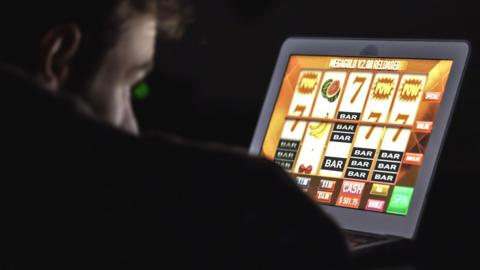 Man staring at an online casino slot machine on laptop computer at night