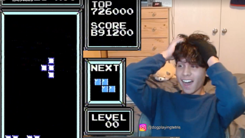 A screenshot taken from Michael Artiaga's Twitch livestream on Twitch, displaying a falling shape on Tetris, with "Level 00" displayed besides it, on the left hand side of the screen. On the right, Michael is reacting with his hands on his head and an expression of disbelief.