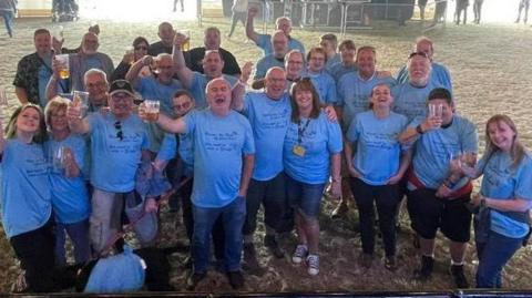 Group people wearing blue t-shirts raising beer glasses