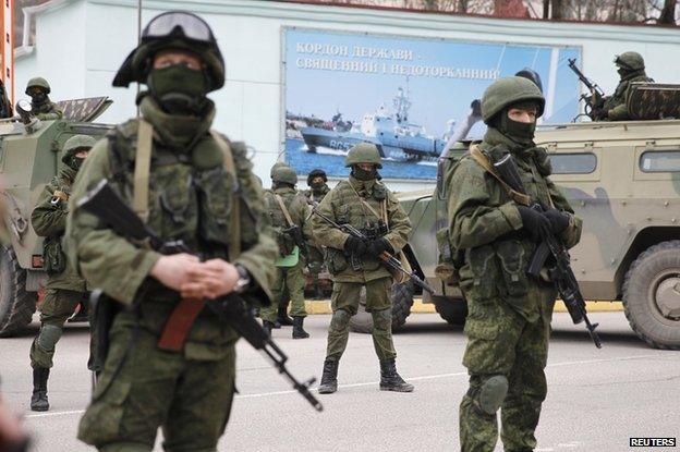 Armed servicemen wait near Russian army vehicles outside a Ukrainian border guard post in the Crimean town of Balaclava March 1, 2014.