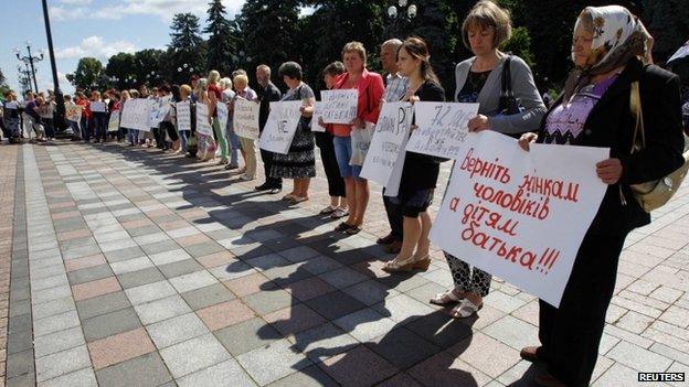 Relatives of men drafted into the army hold placards during a rally to demand their return during a rally near the Ukrainian parliament in Kiev on 2 July 2014.