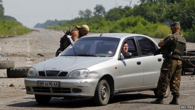 Ukrainian army servicemen check a car at a checkpoint outside the eastern Ukrainian village of Nikishyne (1 August 2014)