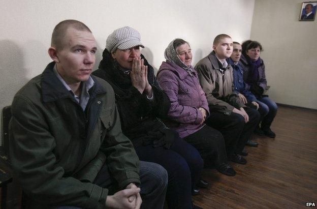 Freed Ukrainian soldiers sit beside their mothers in Luhansk, 26 December