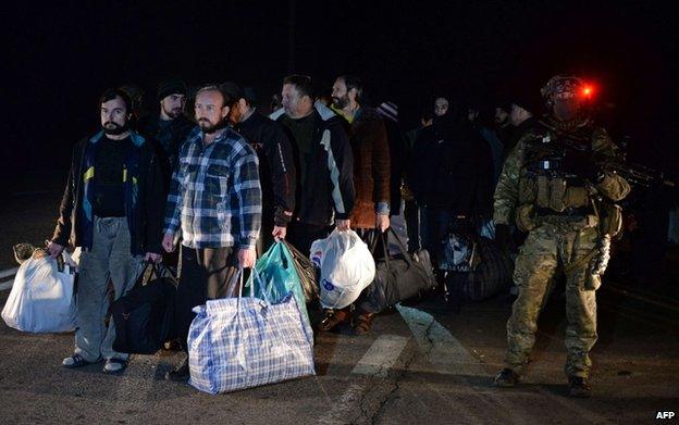 A Ukrainian soldier guards rebel prisoners about to be exchanged for Ukrainian soldiers, 26 December