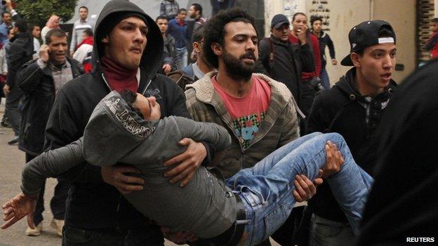 Demonstrators carry an injured protester in Cairo. Photo: 25 January 2015