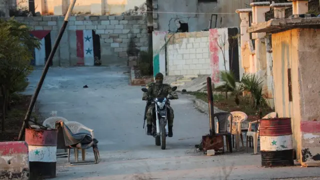 A rebel led by the Islamist militant group Hayat Tahrir al-Sham drives on a motorbike at a checkpoint in al-Rashideen, Aleppo province, Syria