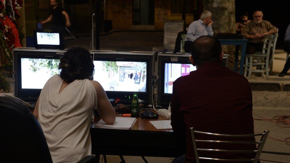 Production crew workers watch as a scene from drama Seksenler is filmed