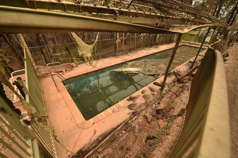 Debris seen around a swimming pool next to the remains of a house destroyed by bushfires