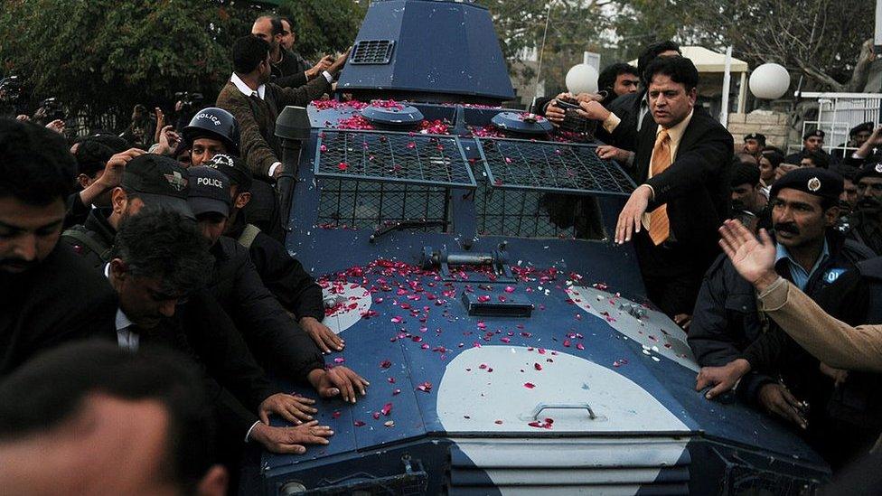 Pakistani police escort an armoured vehicle carrying arrested Pakistani bodyguard Malik Mumtaz Hussain Qadri, the alleged killer of Punjab's governor Salman Taseer, as they leave the anti-terrorist court after a hearing in Rawalpindi on 6 January 2011.