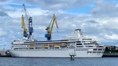 El barco amarrado en el puerto y rodeado de grúas. 