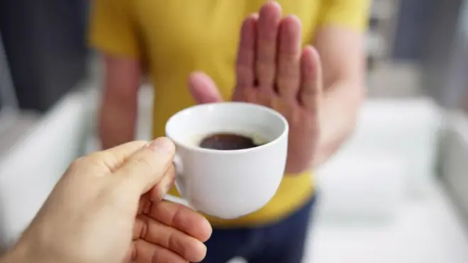 Une main qui refuse une tasse de café