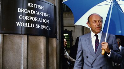 John Tusa seen in the late 1980s, outside Bush House the former BBC World Service headquarters in London with an umbrella. 