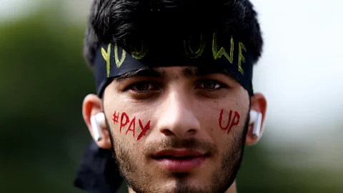 A Nepali activist poses for a photo with slogans calling for climate justice on his face in Lalitpur, Nepal (Credit: Getty Images)