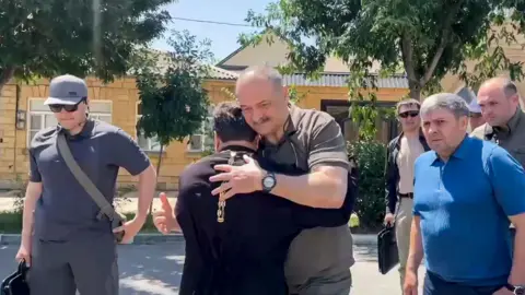 EPA The head of the Dagestan regional administration embraces a priest after the attack