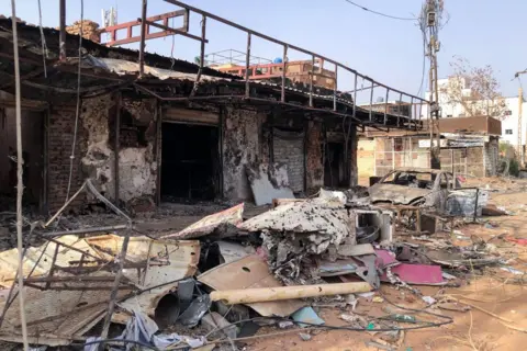 Getty Images Heavily damaged shops in Omdurman, which are totally burnt out, piles of damaged debris out the front and also a burnt out car on May 30, 2024.