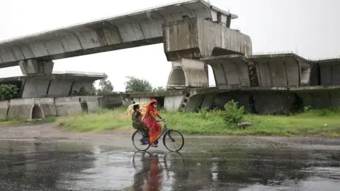 EPA A woman on a bicycle rides in heavy rain