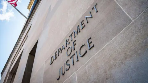 The words "Department of Justice" on a wall on the side of the Department of Justice building in the US.