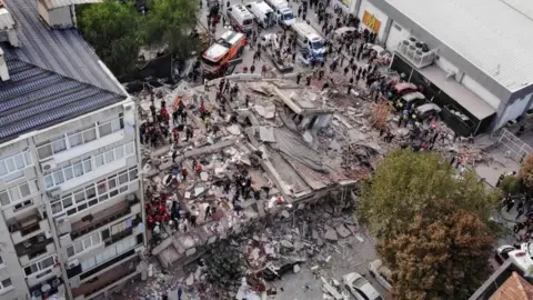 Reuters Rescuers search for survivors at a collapsed building in Izmir, Turkey. Photo: 30 October 2020