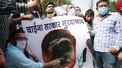 EPA Activists of Bharatiya Janata Party"s (BJP) Youth Wing put black paint on a portrait of Chinese President Xi Jinping, with a garland of shoes put around it, during a protest against China, in Amritsar, India, 22 June 2020.