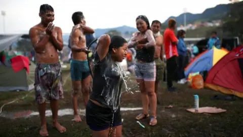 Reuters Colombian indigenous people take a bath as they prepare to participate in a protest in Fusagasuga, Colombia October 18, 2020.