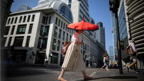 EPA A woman walks through the city of London with an umbrella