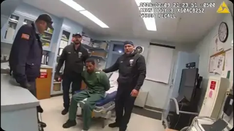 Screenshot of bodycam footage showing officers holding down Robert Brooks in a prison infirmary.