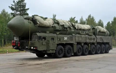 A green Yars-M missile complex on a mobile launcher with eight large wheels at Russian strategic missile forces base