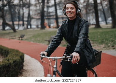 Una mujer de negocios joven elegante y atractiva que lleva auriculares mientras monta en bicicleta en un entorno urbano del parque, exudando confianza y alegría.