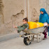 Niñas afganas transportan bidones de agua por una calle de Kandahar.