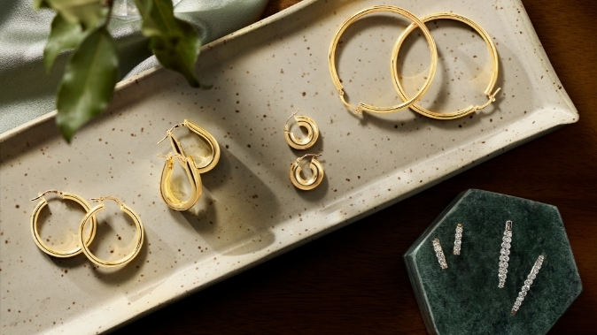 Image of gold hoop earrings laying in a jewelry box and jewelry dish.