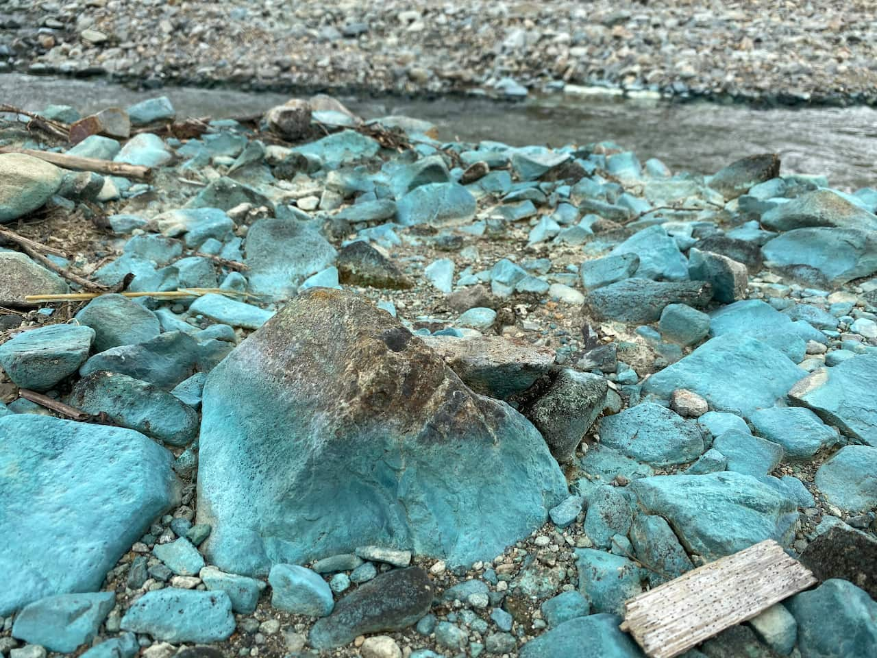 Rocks coloured grey-blue on the river bank - the result of copper pollution and mining tailings.