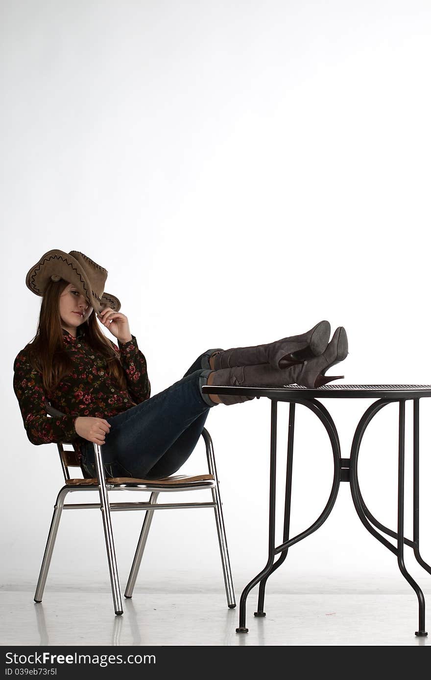 Attractive cowgirl with legs on table