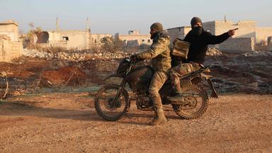 Dschihadisten fahren auf einem Motorrad durch ein Dorf bei Idlib