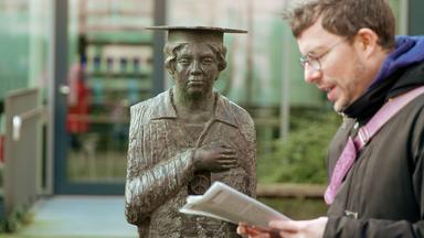 Ein Mann liest einen Text vor der Helenenstatue.