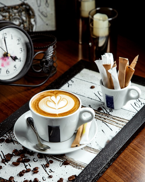 Foto grátis cappuccino com imagens de flores em cima da mesa