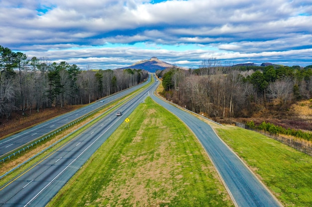 Foto grátis foto aérea de uma estrada com a montanha pilot na carolina do norte, eua, e um céu azul nublado